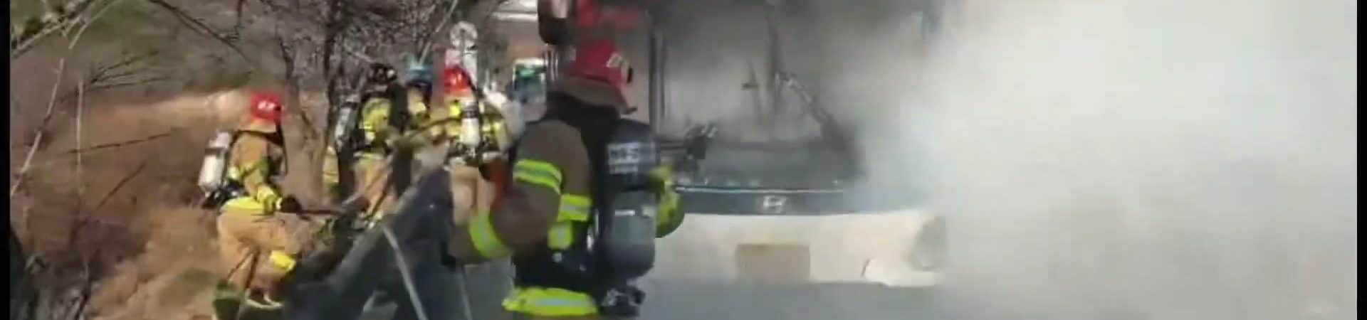 Imagem do ônibus elétrico da Hyundai incendiado, enquanto bombeiros tentam controlar as chamas