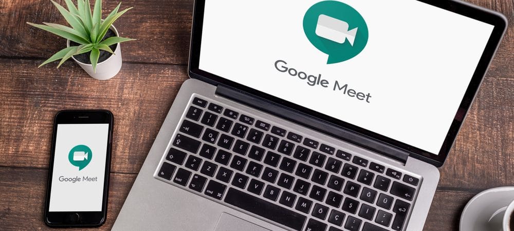 Imagem mostra um notebook e um celular em cima de uma mesa de madeira, ambos estão com o ícone do aplicativo do Google Meet na tela