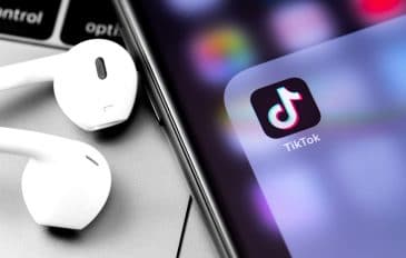 Fones de ouvido ao lado de um celular com a logo do app do TikTok