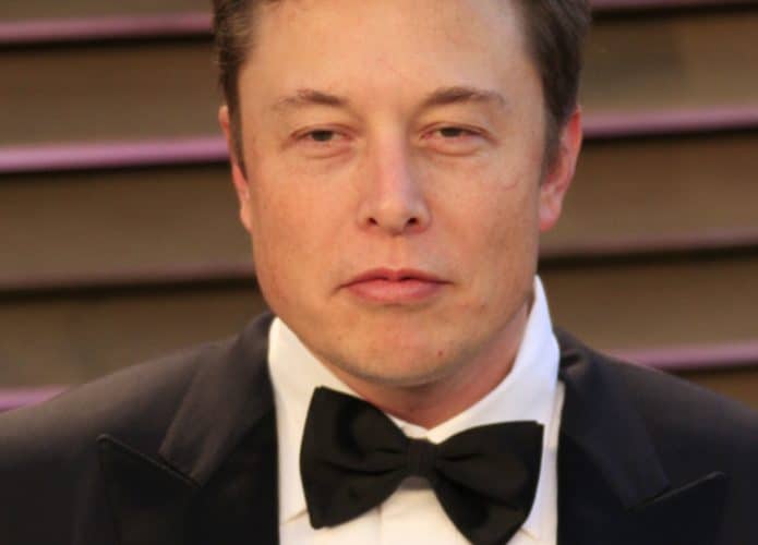 Elon Musk é exibido na imagem, usando gravata borboleta preta, paletó preto e camisa branca, em um evento de gala