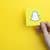 Em fundo amarelo, imagem mostra uma mão segurando um cartão que tem uma ilustração do fantasma, logomarca da rede social Snapchat