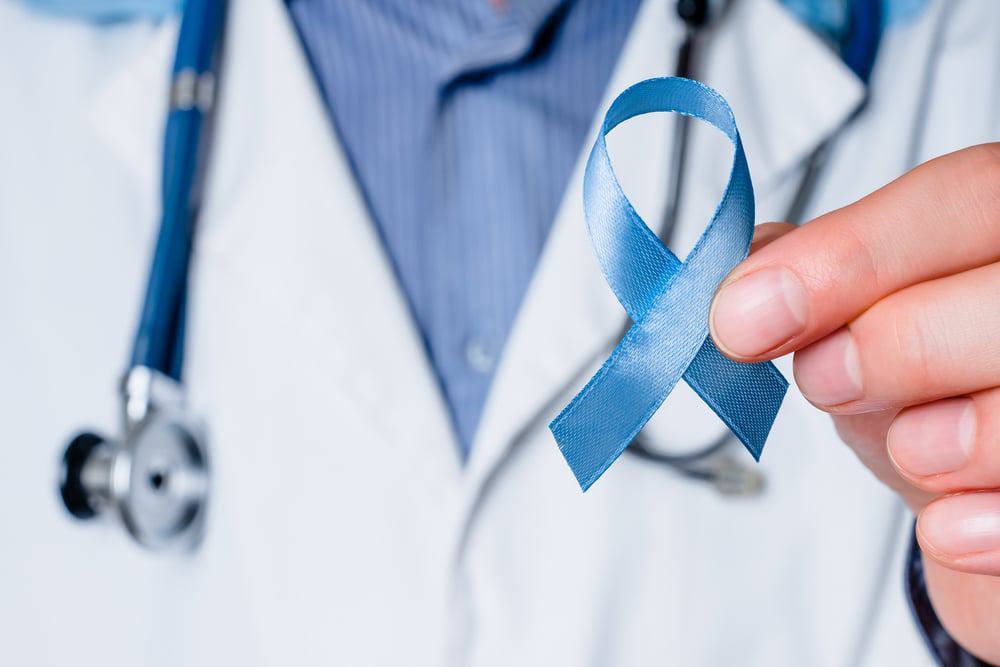 Médico segurando uma fita azul em representação a consciência do câncer de próstata
