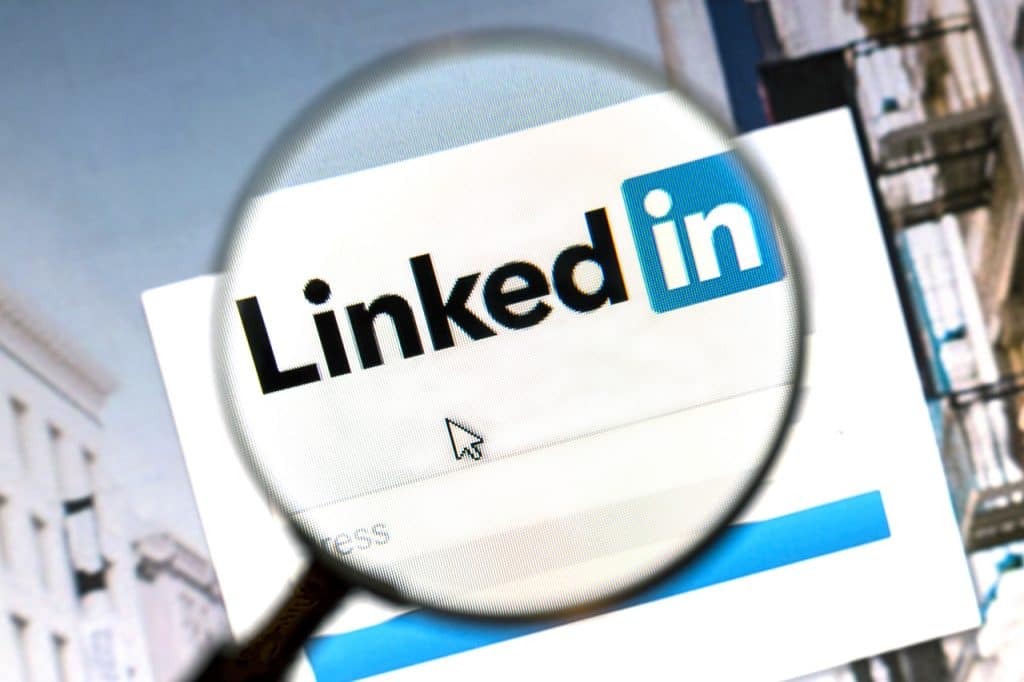 Imagem mostra o logotipo do LinkedIn aberto em uma página web; uma lupa está posicionada em cima do logotipo, aumentando seu tamanho