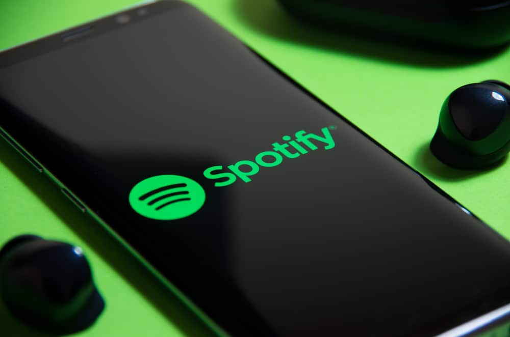 Logo do Spotify aparece na tela de um smartphone colocado em cima de um fundo verde limão