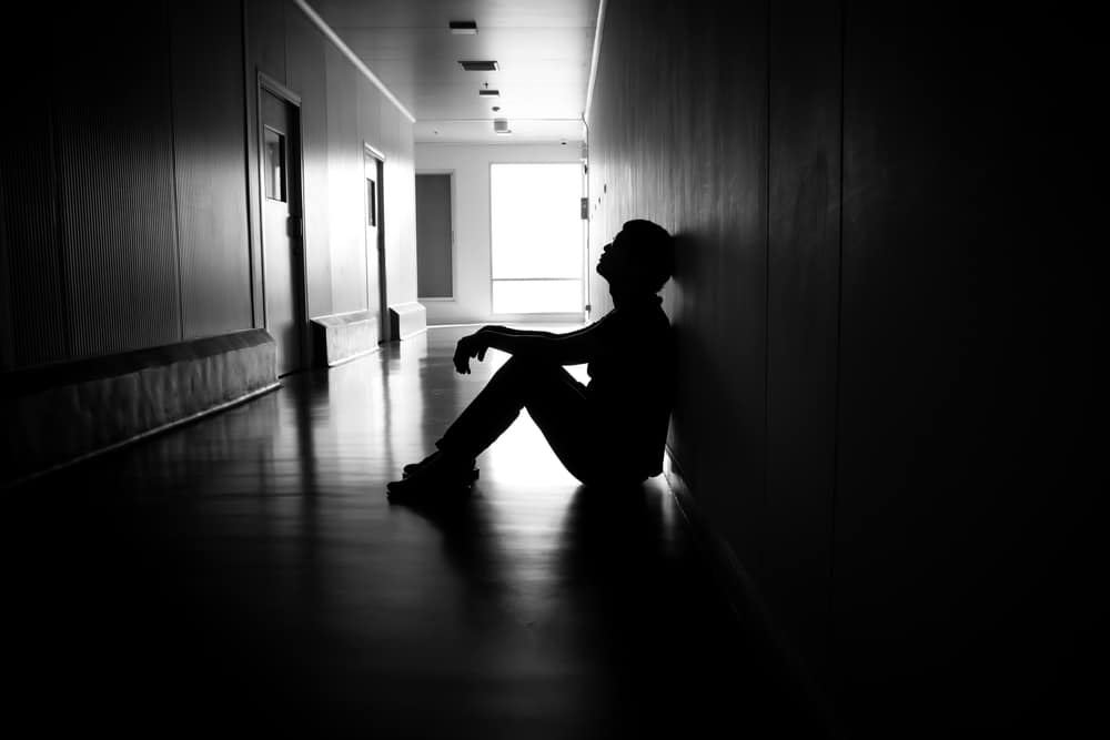 Homem sentado em um corredor escuro