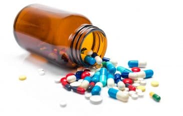 Imagem mostra várias pílulas medicinais despejadas de um frasco de vidro