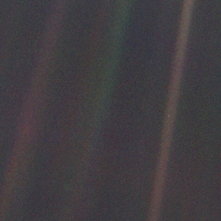 Nesta imagem feita pela Voyager-1 em 1990, a Terra é um minúsculo ponto azul no meio do raio de luz da direita
