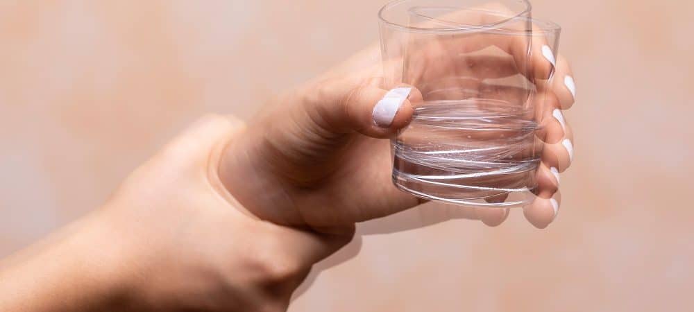 mulher com Parkinson segurando copo de água