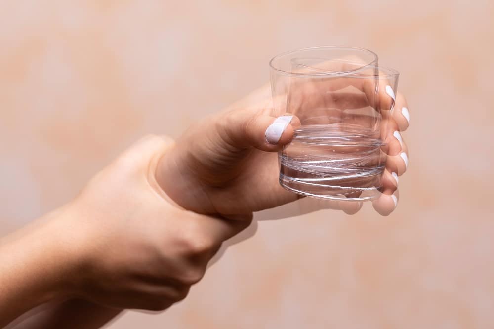 mulher com Parkinson segurando copo de água