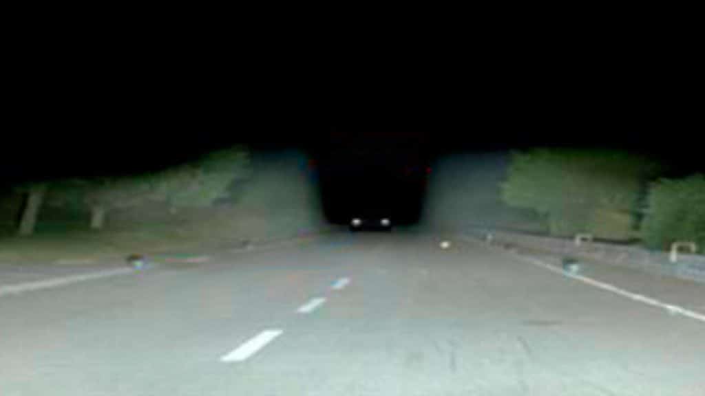 estrada iluminada por farol mostrando carro vindo na direção oposta