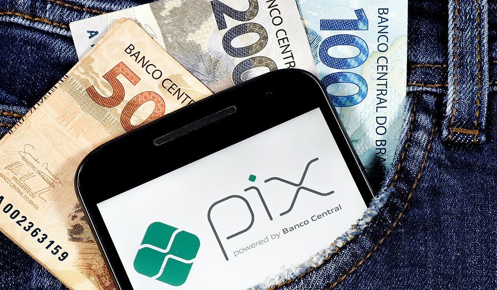 Bolso com dinheiro e celular mostrando o PIX