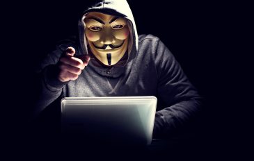 hacker com mascara do grupo anonymous apontando para você