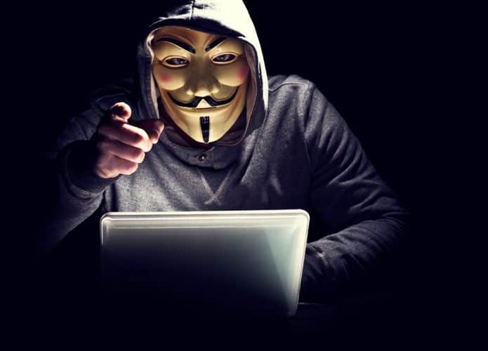 hacker com mascara do grupo anonymous apontando para você