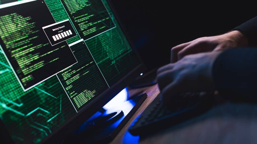 homem branco na frente de computador hackeando sistema