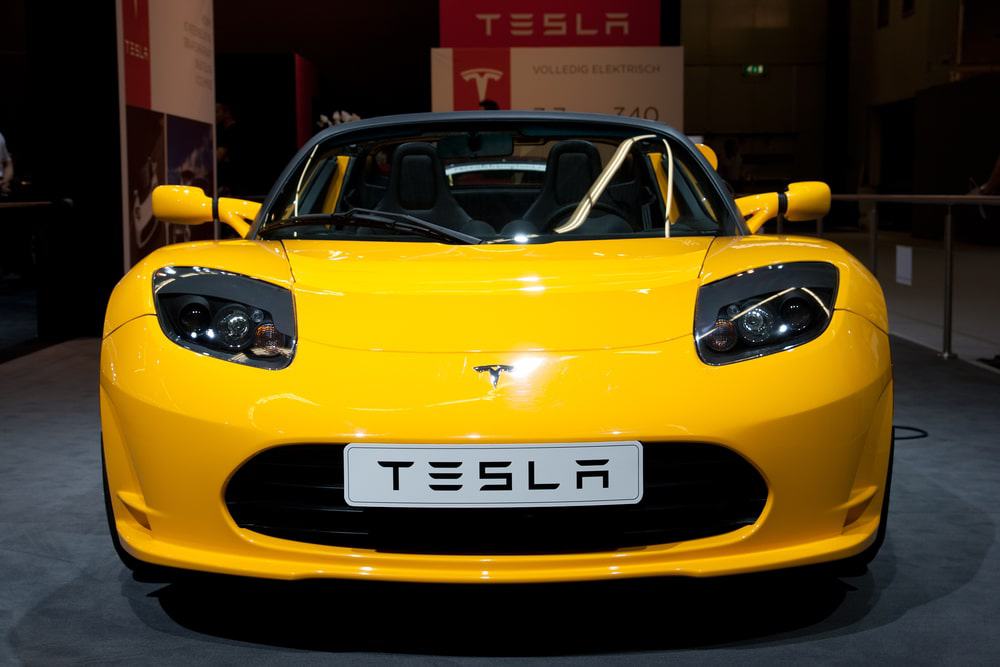 Imagem mostra um carro na cor amarela, da Tesla, visto de frente