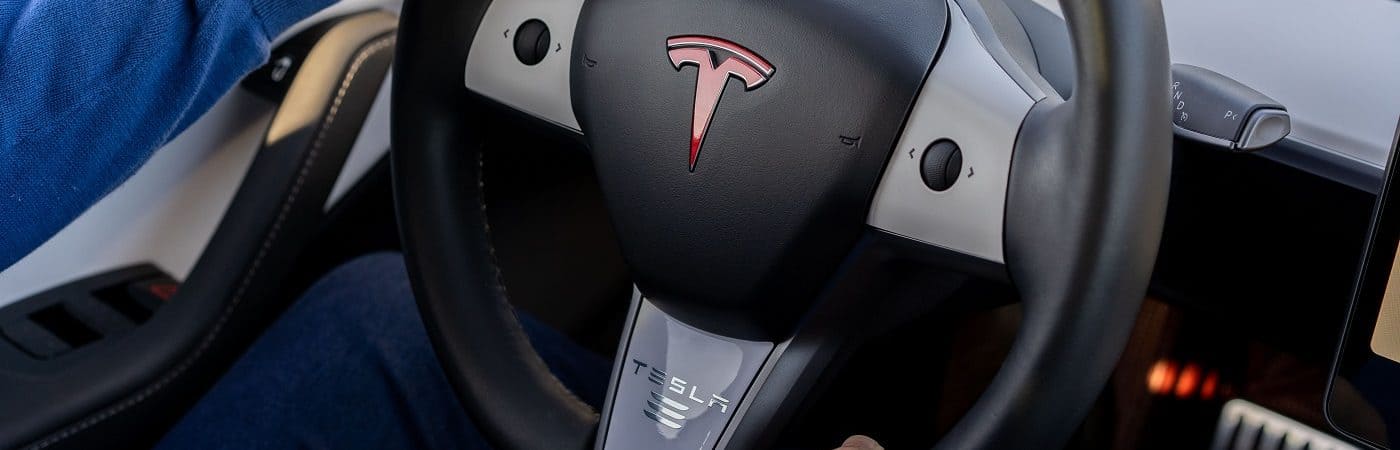 Homem segurando volante de um automóvel da Tesla