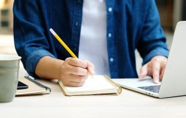 Pessoa estudando com caderno e computador