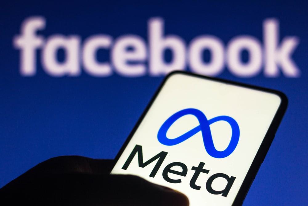 Logotipo da Meta exibido em um smartphone e, ao fundo, o logotipo do Facebook