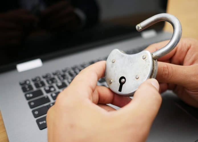 Um cadeado sendo aberto na frente de um notebook para ilustrar um futuro seguro e sem senhas