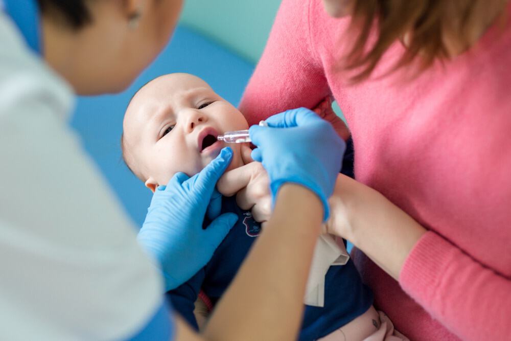 Bebê recebendo gotas de vacina na boca