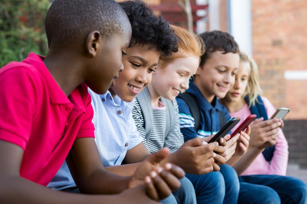 Crianças usando celular na escola; uso de smartphones por crianças.