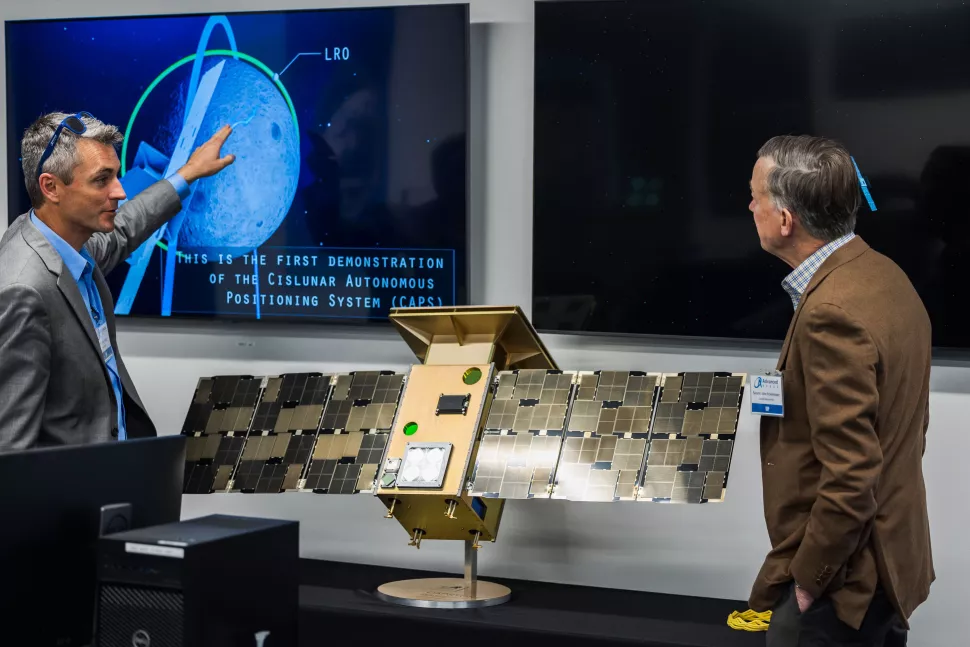 O CTO da Advanced Space, Jeffrey Parker, explica detalhes da missão CAPSTONE ao senador John Hickenlooper, do Colorado, usando um modelo de tamanho real do satélite