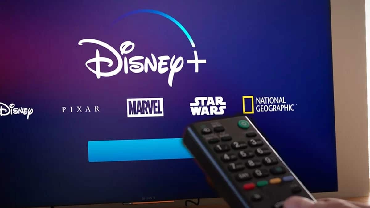 Pessoa apontando controle para TV com tela de login do Disney Plus