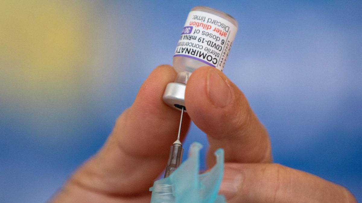 Enfermeiro carregando dose da vacina bivalente contra Covid numa agulha de injeção
