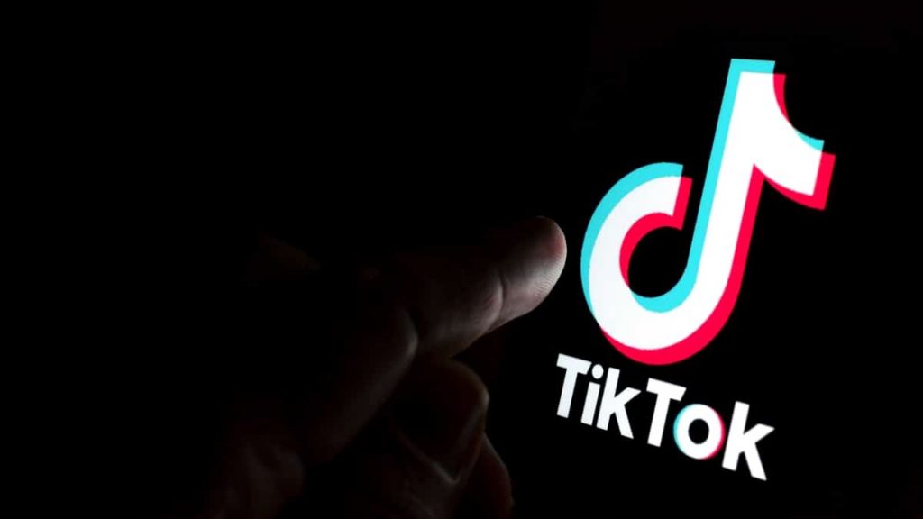 Pessoa com dedo sobre logomarca do TikTok na tela de um celular
