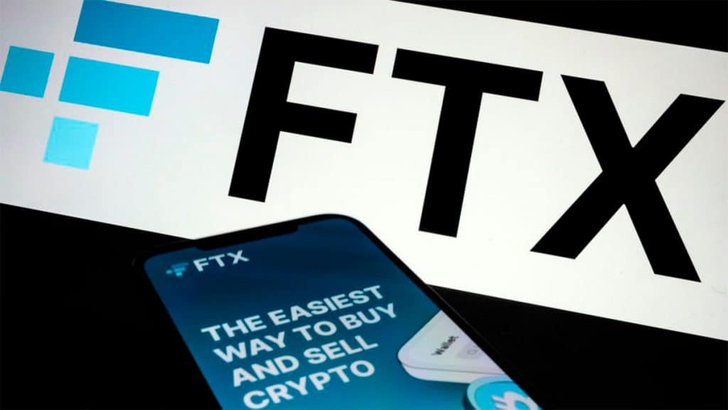 Celular e tela de computador com logomarca da FTX, empresa fundada por Sam Bankman-Fried